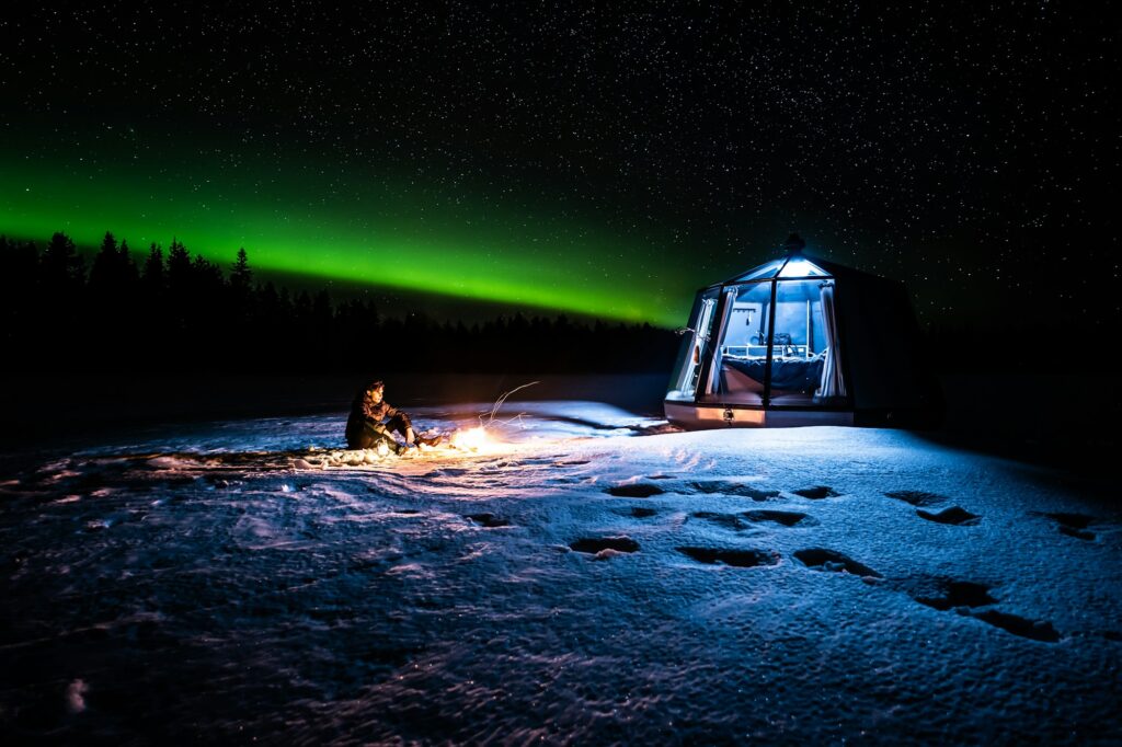 Aurora boreal sobre iglu de vidro na Lapônia finlandesa
