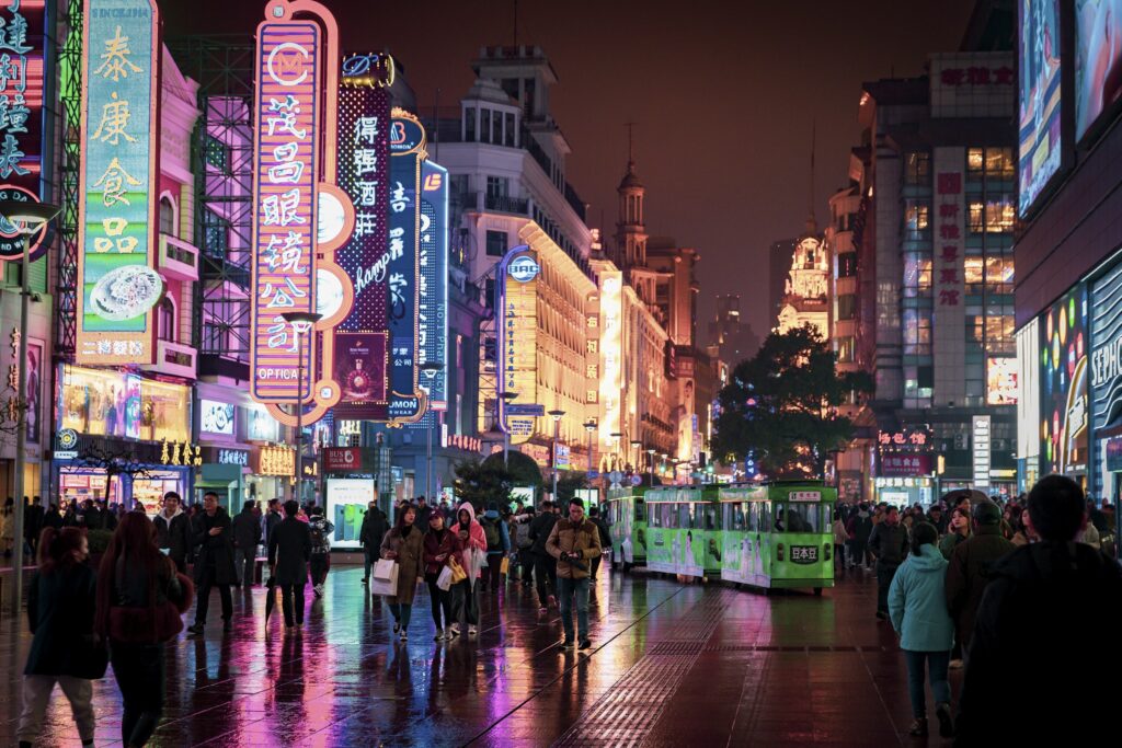 Nanjing Road, em Xangai, iluminada à noite com letreiros de neon e movimento de pedestres