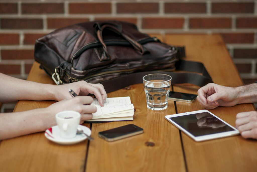 Duas pessoas em reunião de negócios com tablet, café e anotações sobre a mesa