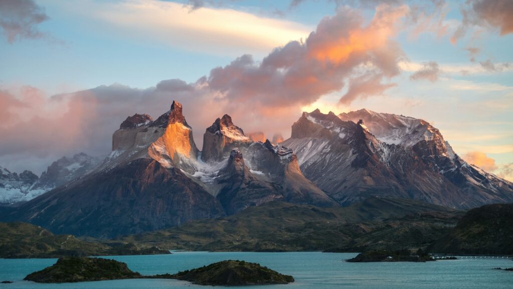 Torres del Paine ao amanhecer, com lago em primeiro plano, na Patagônia chilena